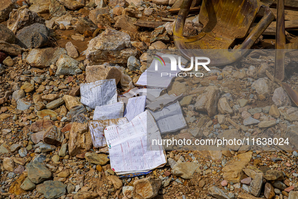 Scattered book papers lie in front of damaged homes in the Bhardev region of southern Lalitpur, Nepal, on October 5, 2024. 