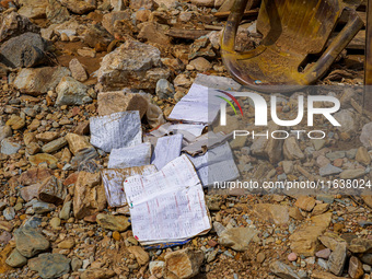 Scattered book papers lie in front of damaged homes in the Bhardev region of southern Lalitpur, Nepal, on October 5, 2024. (