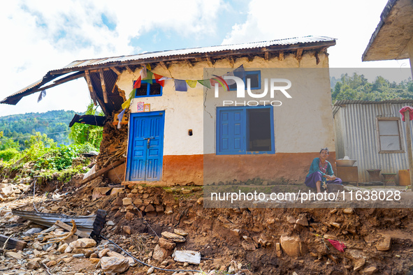 A woman sits in front of her flood-damaged home from the Nakhu River Flooding in the Bhardev region of southern Lalitpur, Nepal, on October...