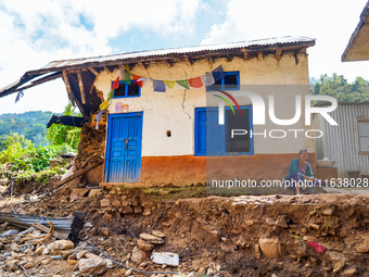 A woman sits in front of her flood-damaged home from the Nakhu River Flooding in the Bhardev region of southern Lalitpur, Nepal, on October...