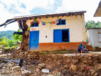 A woman sits in front of her flood-damaged home from the Nakhu River Flooding in the Bhardev region of southern Lalitpur, Nepal, on October...