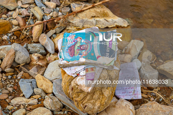 Scattered book papers lie in front of damaged homes in the Bhardev region of southern Lalitpur, Nepal, on October 5, 2024. 