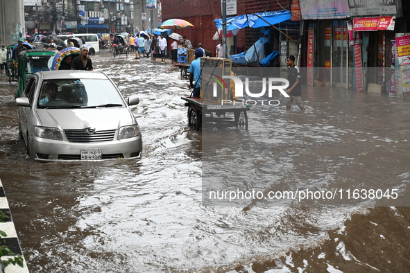 Vehicles and rickshaws drive with passengers through the waterlogged streets of Dhaka, Bangladesh, on October 5, 2024, after heavy rainfalls...