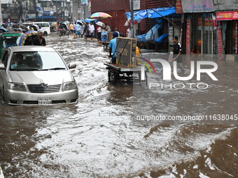 Vehicles and rickshaws drive with passengers through the waterlogged streets of Dhaka, Bangladesh, on October 5, 2024, after heavy rainfalls...