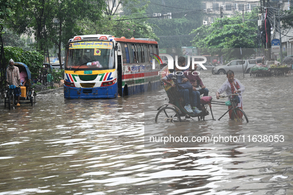 Vehicles and rickshaws drive with passengers through the waterlogged streets of Dhaka, Bangladesh, on October 5, 2024, after heavy rainfalls...