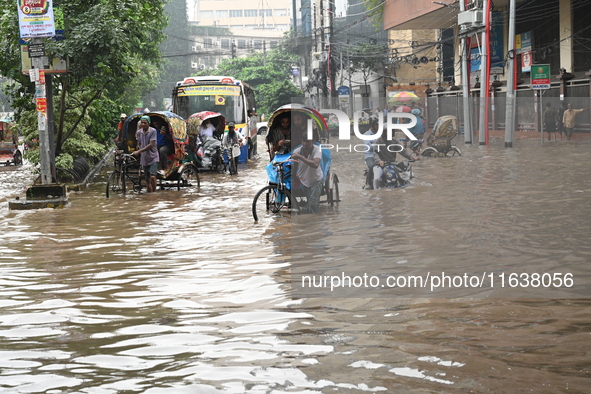 Vehicles and rickshaws drive with passengers through the waterlogged streets of Dhaka, Bangladesh, on October 5, 2024, after heavy rainfalls...