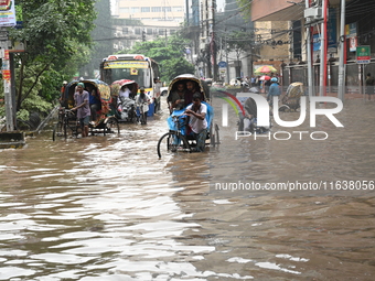 Vehicles and rickshaws drive with passengers through the waterlogged streets of Dhaka, Bangladesh, on October 5, 2024, after heavy rainfalls...