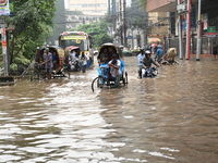 Vehicles and rickshaws drive with passengers through the waterlogged streets of Dhaka, Bangladesh, on October 5, 2024, after heavy rainfalls...