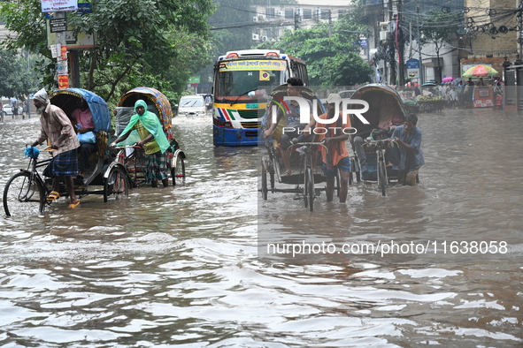 Vehicles and rickshaws drive with passengers through the waterlogged streets of Dhaka, Bangladesh, on October 5, 2024, after heavy rainfalls...