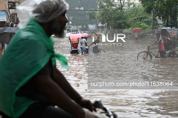 Vehicles and rickshaws drive with passengers through the waterlogged streets of Dhaka, Bangladesh, on October 5, 2024, after heavy rainfalls...