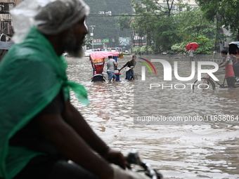 Vehicles and rickshaws drive with passengers through the waterlogged streets of Dhaka, Bangladesh, on October 5, 2024, after heavy rainfalls...