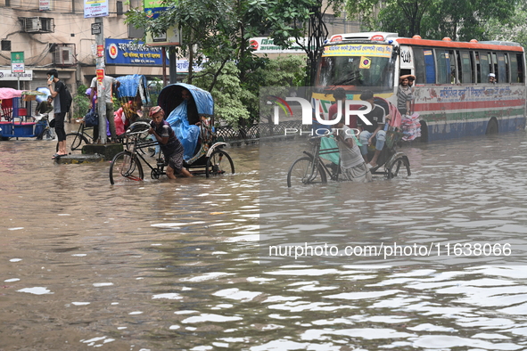 Vehicles and rickshaws drive with passengers through the waterlogged streets of Dhaka, Bangladesh, on October 5, 2024, after heavy rainfalls...