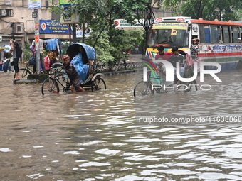 Vehicles and rickshaws drive with passengers through the waterlogged streets of Dhaka, Bangladesh, on October 5, 2024, after heavy rainfalls...