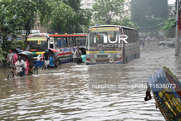 Vehicles and rickshaws drive with passengers through the waterlogged streets of Dhaka, Bangladesh, on October 5, 2024, after heavy rainfalls...