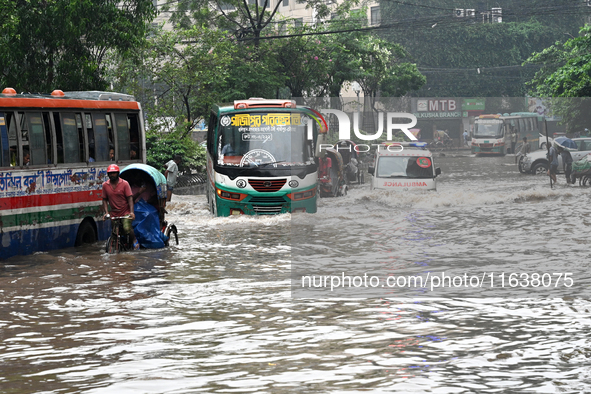 Vehicles and rickshaws drive with passengers through the waterlogged streets of Dhaka, Bangladesh, on October 5, 2024, after heavy rainfalls...