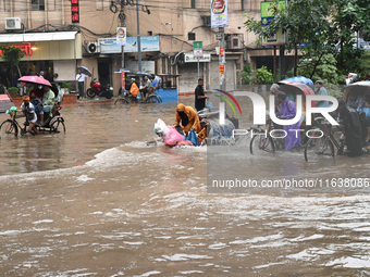 Vehicles and rickshaws drive with passengers through the waterlogged streets of Dhaka, Bangladesh, on October 5, 2024, after heavy rainfalls...