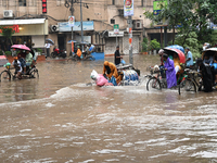 Vehicles and rickshaws drive with passengers through the waterlogged streets of Dhaka, Bangladesh, on October 5, 2024, after heavy rainfalls...