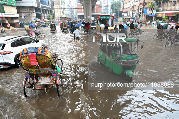 Vehicles and rickshaws drive with passengers through the waterlogged streets of Dhaka, Bangladesh, on October 5, 2024, after heavy rainfalls...