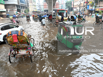 Vehicles and rickshaws drive with passengers through the waterlogged streets of Dhaka, Bangladesh, on October 5, 2024, after heavy rainfalls...