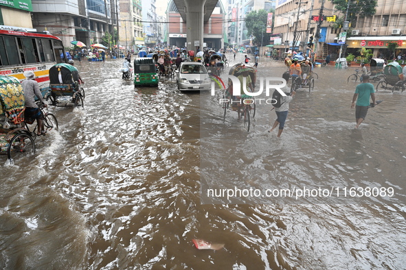 Vehicles and rickshaws drive with passengers through the waterlogged streets of Dhaka, Bangladesh, on October 5, 2024, after heavy rainfalls...