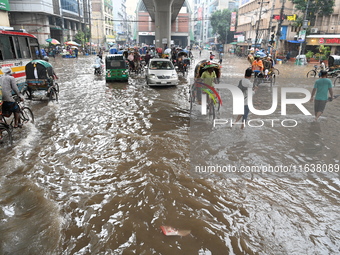 Vehicles and rickshaws drive with passengers through the waterlogged streets of Dhaka, Bangladesh, on October 5, 2024, after heavy rainfalls...