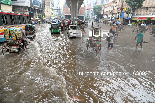 Vehicles and rickshaws drive with passengers through the waterlogged streets of Dhaka, Bangladesh, on October 5, 2024, after heavy rainfalls...