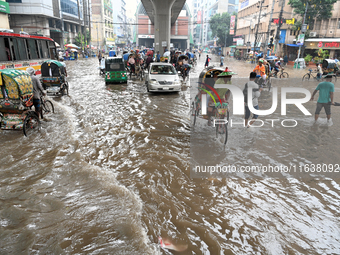 Vehicles and rickshaws drive with passengers through the waterlogged streets of Dhaka, Bangladesh, on October 5, 2024, after heavy rainfalls...