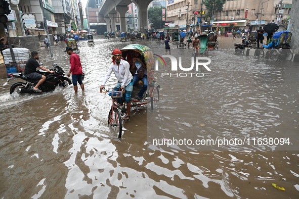 Vehicles and rickshaws drive with passengers through the waterlogged streets of Dhaka, Bangladesh, on October 5, 2024, after heavy rainfalls...