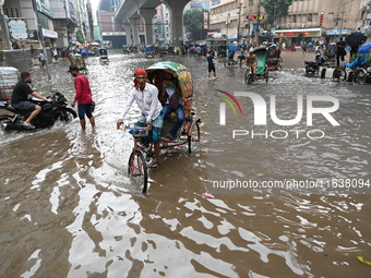 Vehicles and rickshaws drive with passengers through the waterlogged streets of Dhaka, Bangladesh, on October 5, 2024, after heavy rainfalls...