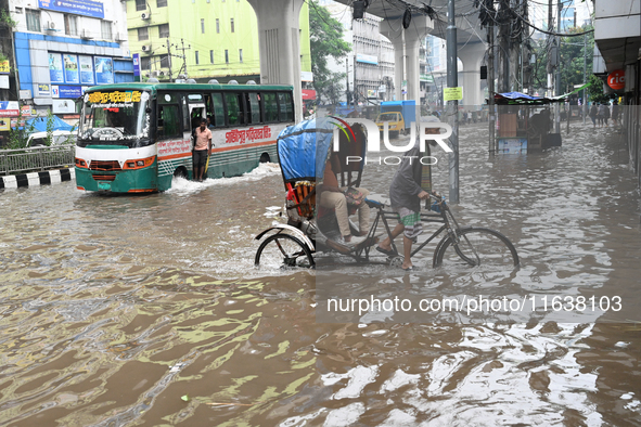 Vehicles and rickshaws drive with passengers through the waterlogged streets of Dhaka, Bangladesh, on October 5, 2024, after heavy rainfalls...