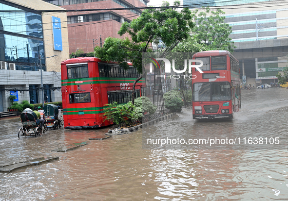 Vehicles and rickshaws drive with passengers through the waterlogged streets of Dhaka, Bangladesh, on October 5, 2024, after heavy rainfalls...