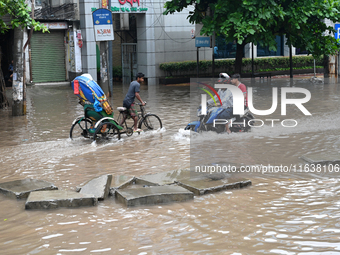 Vehicles and rickshaws drive with passengers through the waterlogged streets of Dhaka, Bangladesh, on October 5, 2024, after heavy rainfalls...