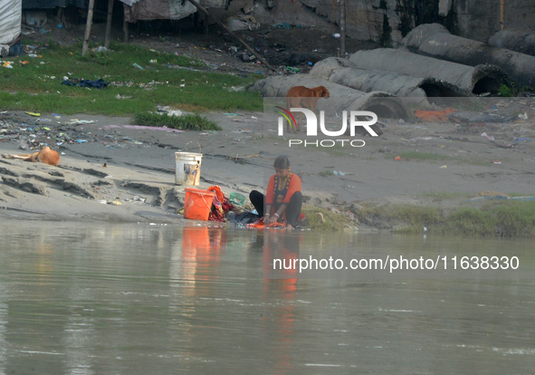 A woman living below the poverty line washes clothes in the Mahananda River in Siliguri, India, on October 5, 2024. River water pollution, d...