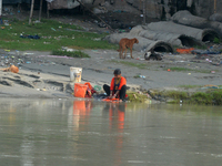 A woman living below the poverty line washes clothes in the Mahananda River in Siliguri, India, on October 5, 2024. River water pollution, d...