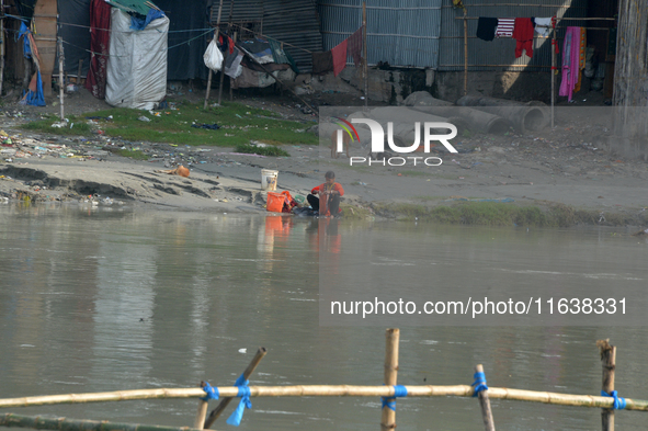 A woman living below the poverty line washes clothes in the Mahananda River in Siliguri, India, on October 5, 2024. River water pollution, d...