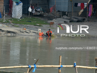 A woman living below the poverty line washes clothes in the Mahananda River in Siliguri, India, on October 5, 2024. River water pollution, d...