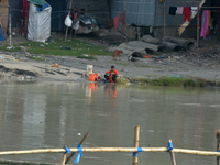 A woman living below the poverty line washes clothes in the Mahananda River in Siliguri, India, on October 5, 2024. River water pollution, d...