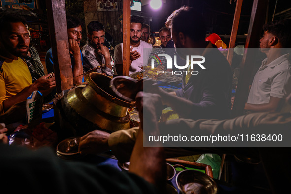 Kashmiri men eat barbecues and other non-vegetarian items from a vendor in Sopore, Jammu and Kashmir, India, on October 5, 2024. 