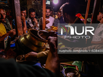 Kashmiri men eat barbecues and other non-vegetarian items from a vendor in Sopore, Jammu and Kashmir, India, on October 5, 2024. (