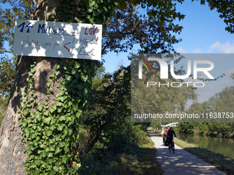 Cyclists ride on the Canal du Midi banks, and a placard reads 'EUR14 bn for the LGV rather than for education or hospitals'. Zadists, or dev...