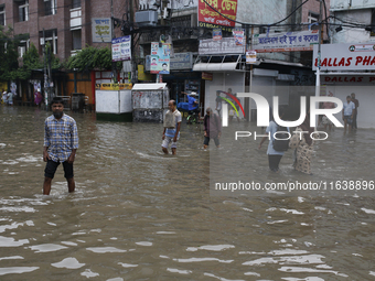 Residents walk through a waterlogged street after heavy rainfall in Dhaka, Bangladesh, on October 5, 2024. The flash flood hits several area...