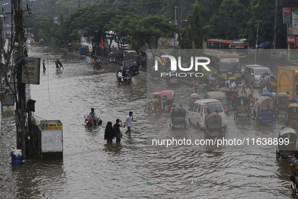 Residents make their way through a waterlogged street after heavy rainfall in Dhaka, Bangladesh, on October 5, 2024. The flash flood hits se...