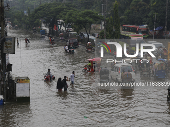 Residents make their way through a waterlogged street after heavy rainfall in Dhaka, Bangladesh, on October 5, 2024. The flash flood hits se...