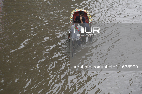 A man pulls his rickshaw through a waterlogged street during rainfall in Dhaka, Bangladesh, on September 26, 2024. The flash flood hits seve...