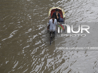 A man pulls his rickshaw through a waterlogged street during rainfall in Dhaka, Bangladesh, on September 26, 2024. The flash flood hits seve...