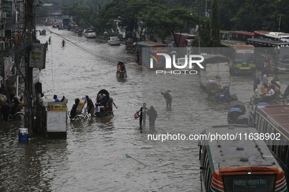 Residents make their way through a waterlogged street after heavy rainfall in Dhaka, Bangladesh, on October 5, 2024. The flash flood hits se...