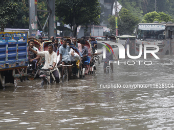 Residents make their way through a waterlogged street after heavy rainfall in Dhaka, Bangladesh, on October 5, 2024. The flash flood hits se...