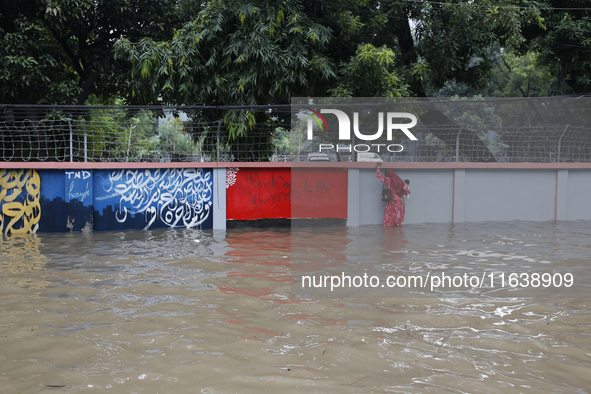 A woman walks through a waterlogged street after heavy rainfall in Dhaka, Bangladesh, on October 5, 2024. The flash flood hits several areas...