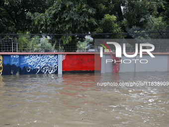 A woman walks through a waterlogged street after heavy rainfall in Dhaka, Bangladesh, on October 5, 2024. The flash flood hits several areas...