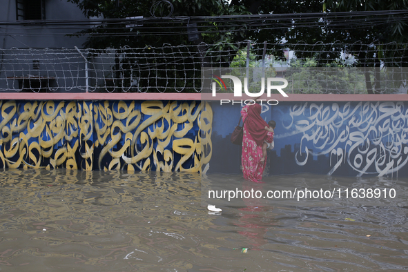 A woman walks through a waterlogged street after heavy rainfall in Dhaka, Bangladesh, on October 5, 2024. The flash flood hits several areas...